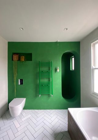 bathroom with green walls and microcement floor
