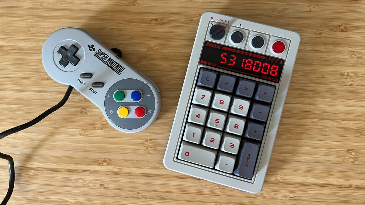 8BitDo Retro 18 Mechanical Numpad with a SNES controller on a wooden desk