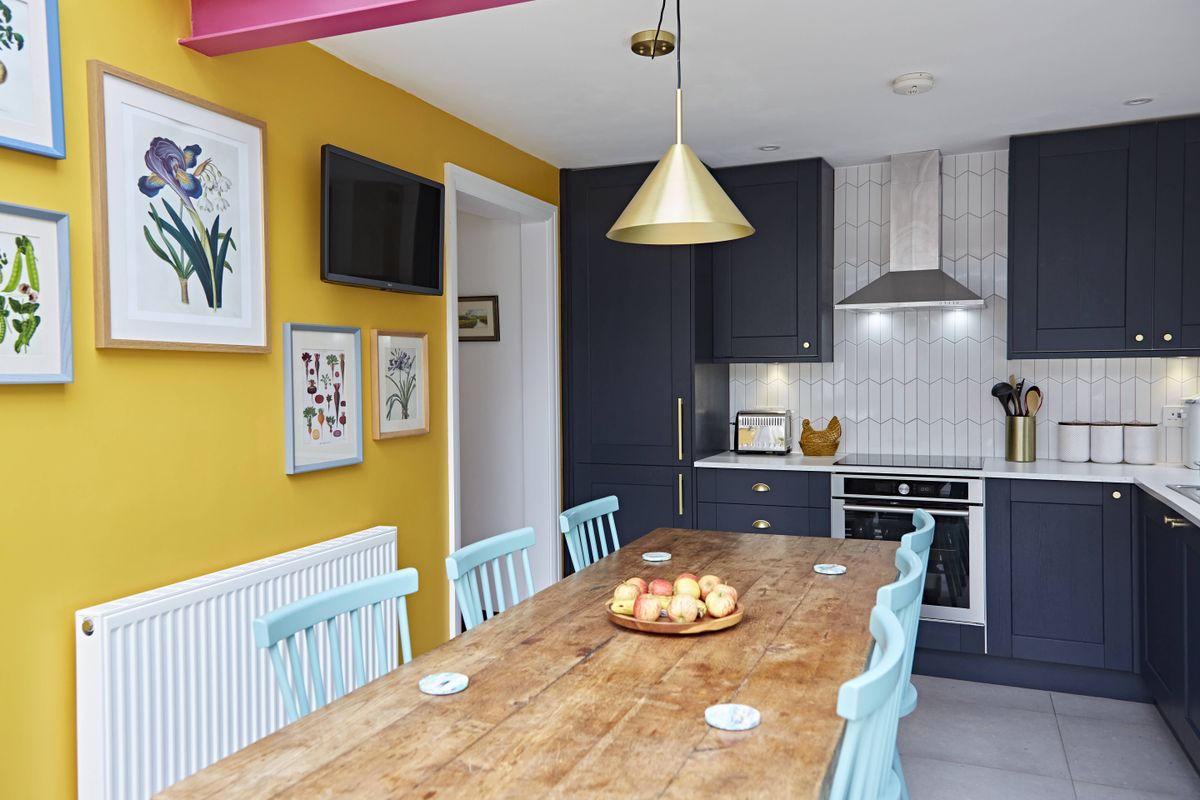 dark blue kitchen diner with bright pink painted steel beam
