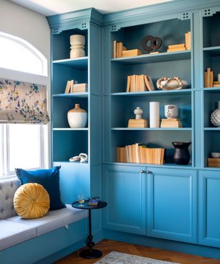 blue book shelving with orange accents and a small reading nook seat