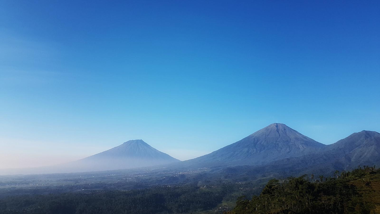 An aerial photograph showing Sundoro and Sumbing side-by-side with near-identical profiles