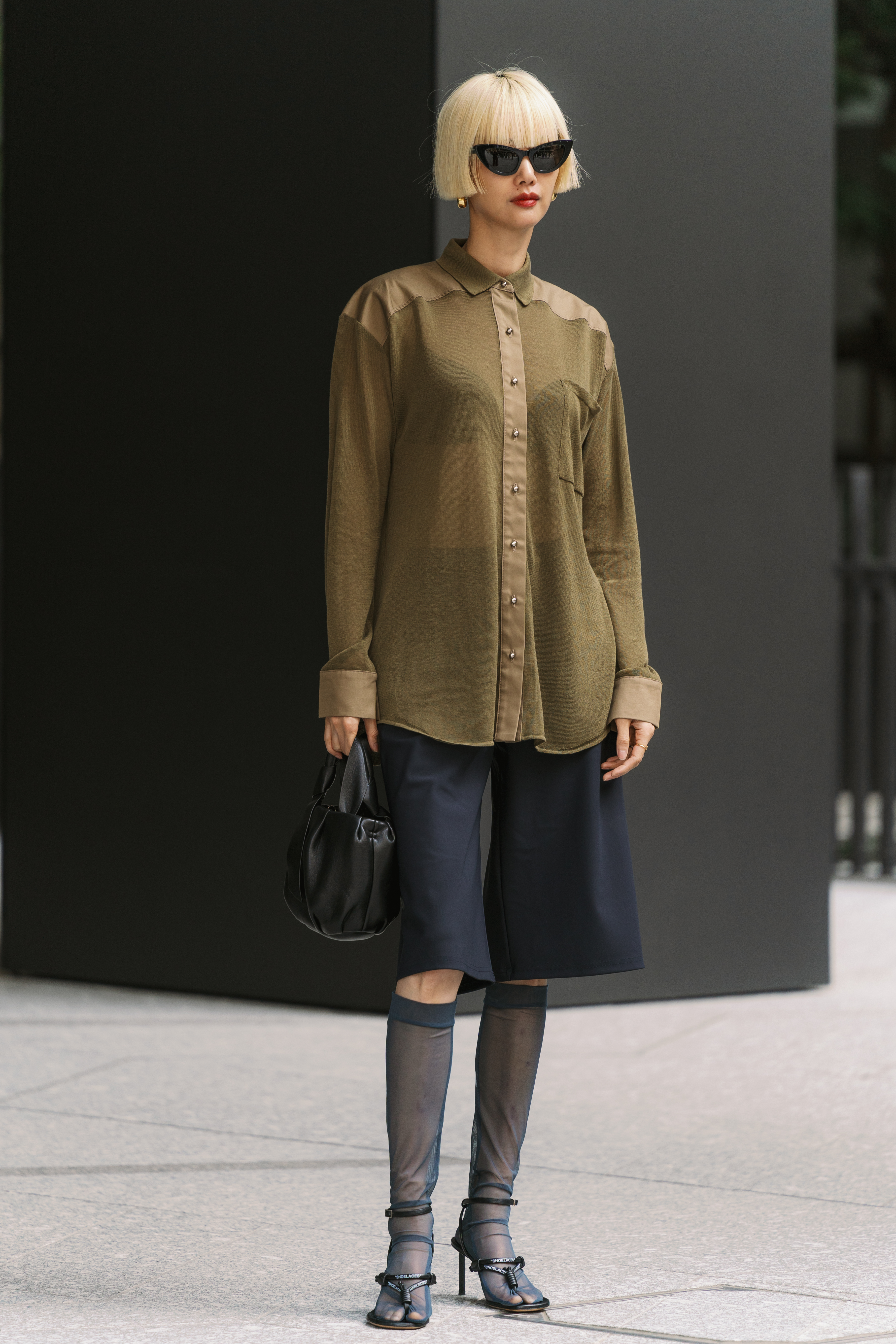Photo of Tokyo street style with model wearing black bermuda shorts.