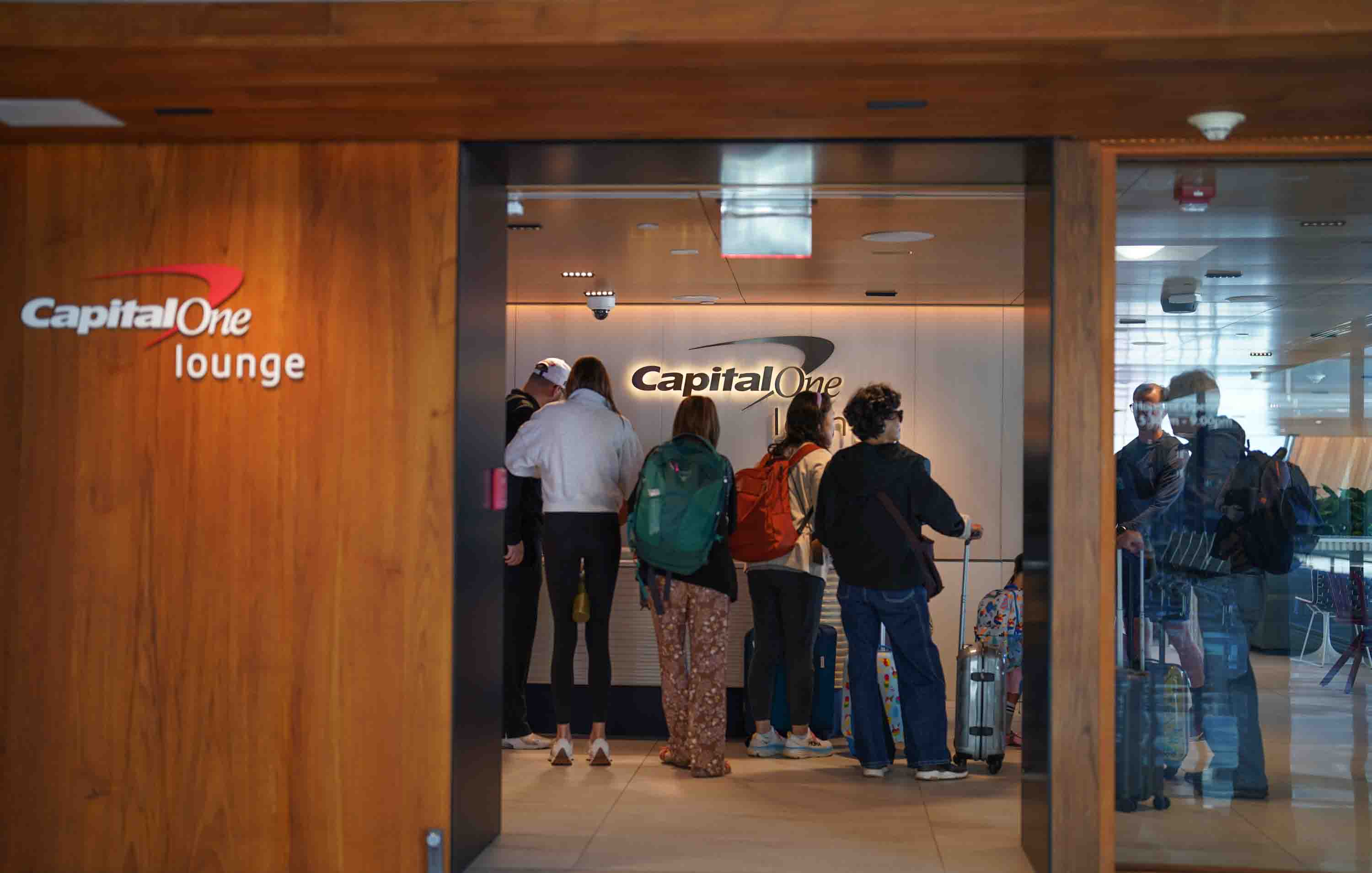 A group of travelers wait to get into a capital one airport lounge.
