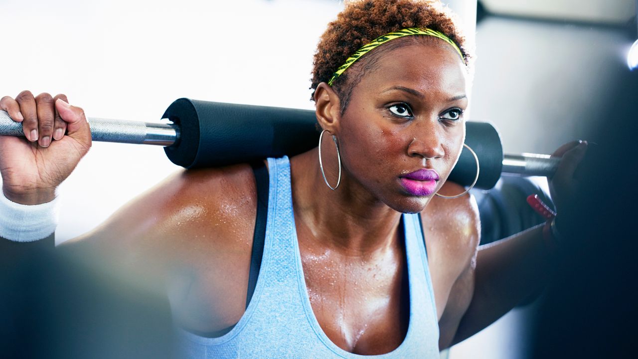 Woman learning how to do a squat in the gym