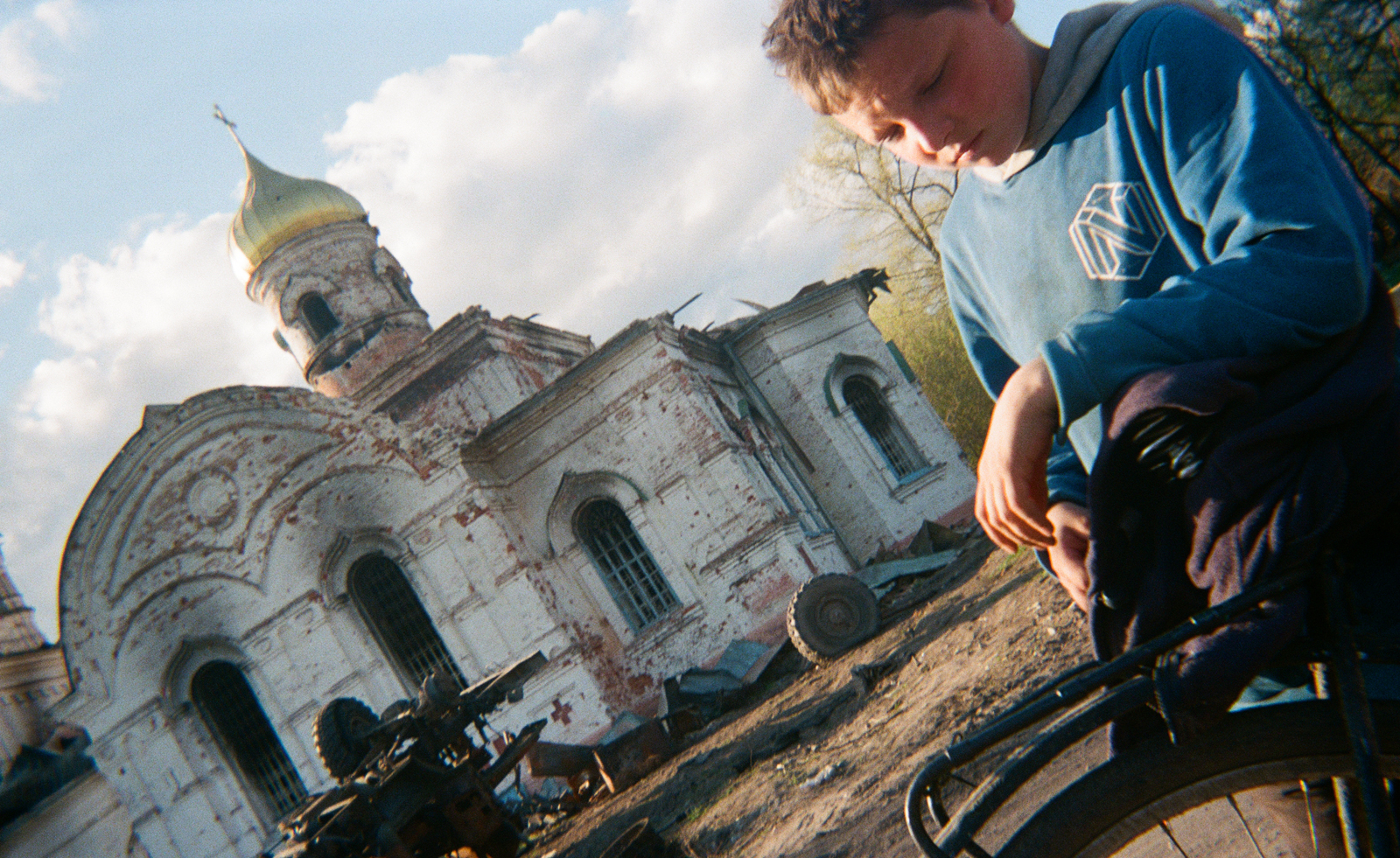 child with bike, and ruins and gun in background