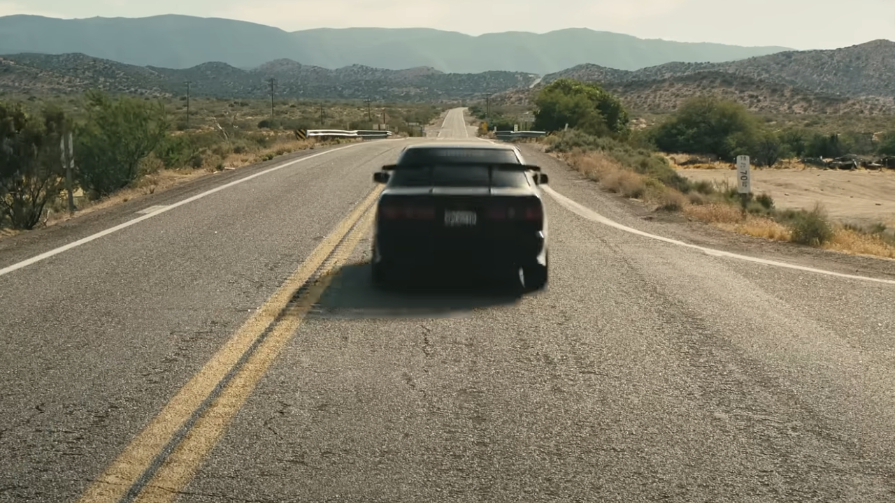 A car zooms along the road in One Battle After Another