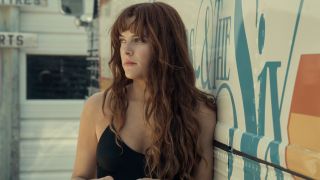 Riley Keough in Daisy Jones and the Six leaning against a tour bus