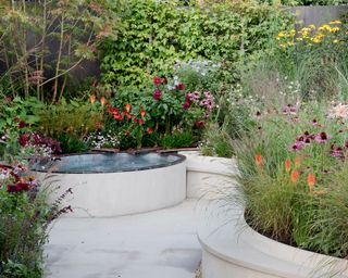 curved garden walls, water feature and flowerbeds in the Finding Our Way: An NHS Tribute Garden at the RHS Chelsea Flower Show 2021