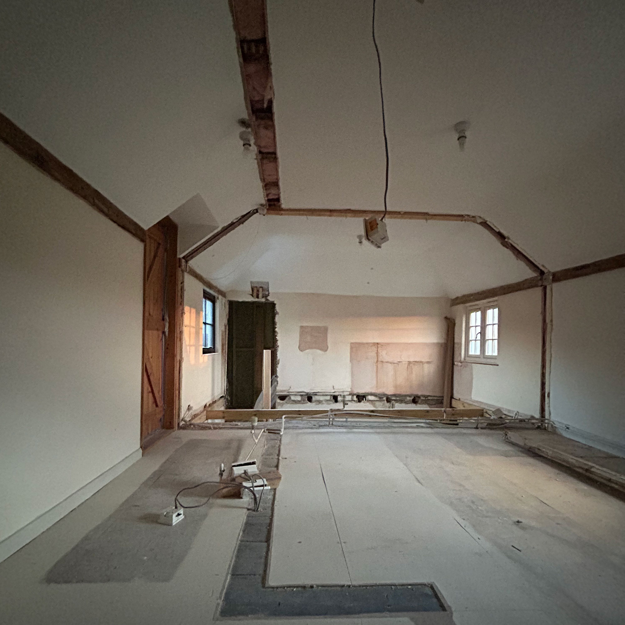 Room mid-renovation with stripped floorboards and exposed wiring