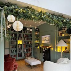 Living room with Christmas garland, paper decorations and green walls.