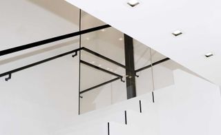 A minimalist metal and glass staircase connects the three floors of the space