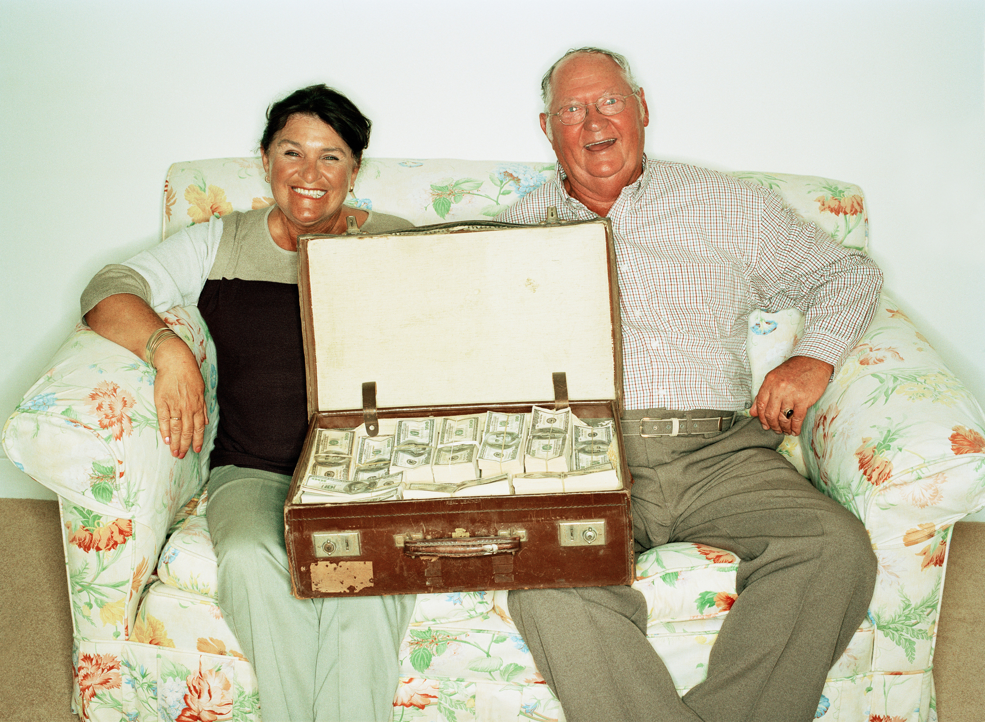 Mature couple on sofa with suitcase full of money