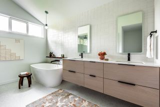 A white bathroom with wooden cabinets and rug with orange detail