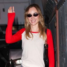 Suki Waterhouse wearing a red and white baseball longsleeve, printed jeans, and yellow sneakers