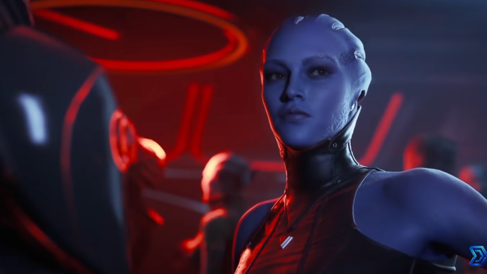 A blue-skinned woman with crest-like head tendrils and facial markings stands in a dimly lit, red-toned room wearing a dark, high-collared outfit.