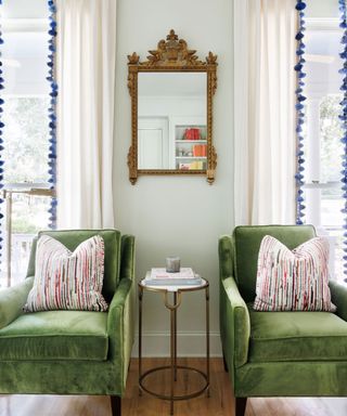 Living room with green velvet chairs, mirror and curtains