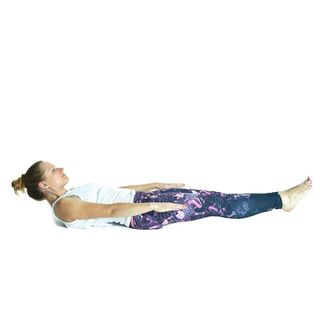 Woman in exercise clothes lying on her back raising and extending her legs, arms, and head, doing a stomach crunch, doing the 100 move