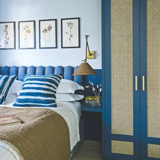 Blue bedroom with light blue walls, dark blue headboard, and dark blue wardrobes with rattan on the doors