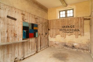 View of a multicoloured painting by Sean Scully in a room with distressed walls at Château de Boisgeloup. The wording 'GARAGE HISPANO-SUISA' can be seen on the wall
