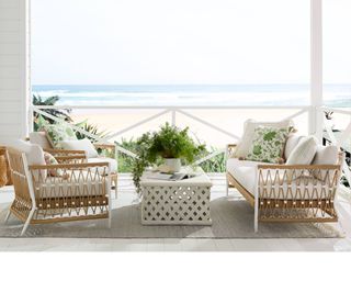 A rattan-effect lounge set on a covered deck overlooking the sea