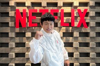 Korean TV personality KIAN84 makes a "fighting" pose in front of a brick wall with a Netflix sign.