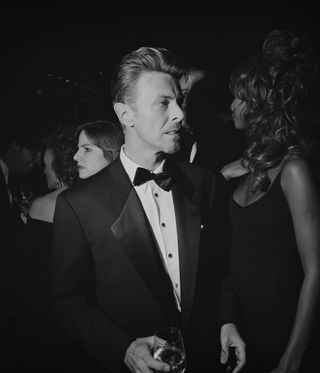 black and white image of man in bow-tie and suit at party, by Larry Fink