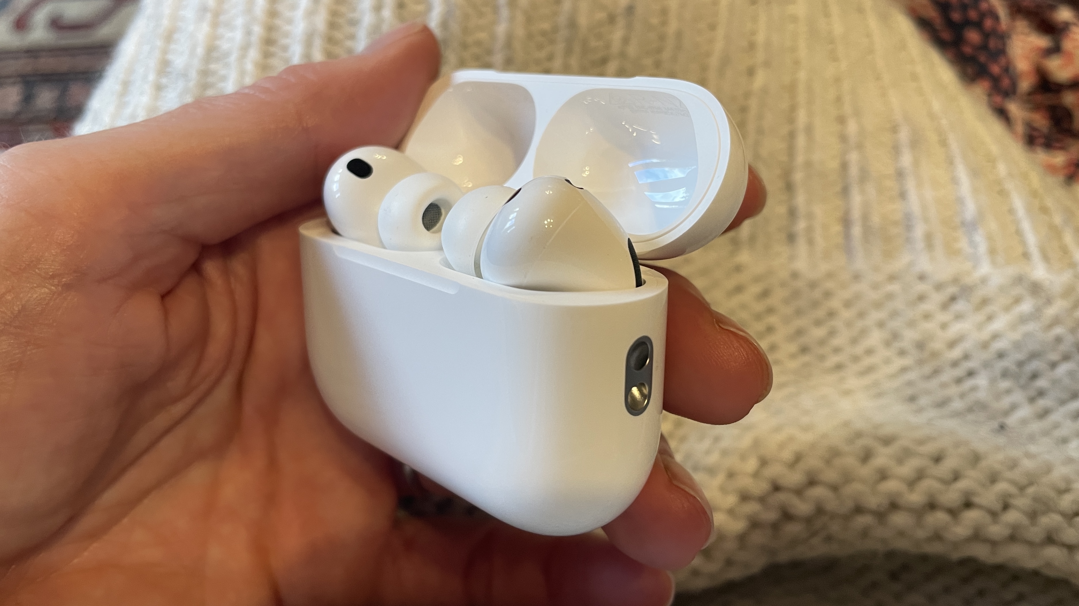AirPods Pro 3 on a woollen background, held in a hand