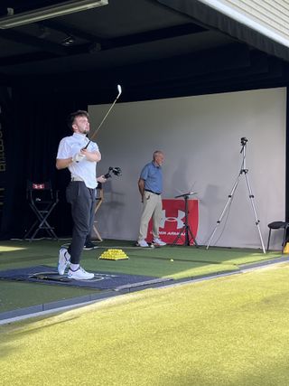 Dan Parker hitting balls in a driving range bay wearing the Under Armour Drive Pro golf shoes