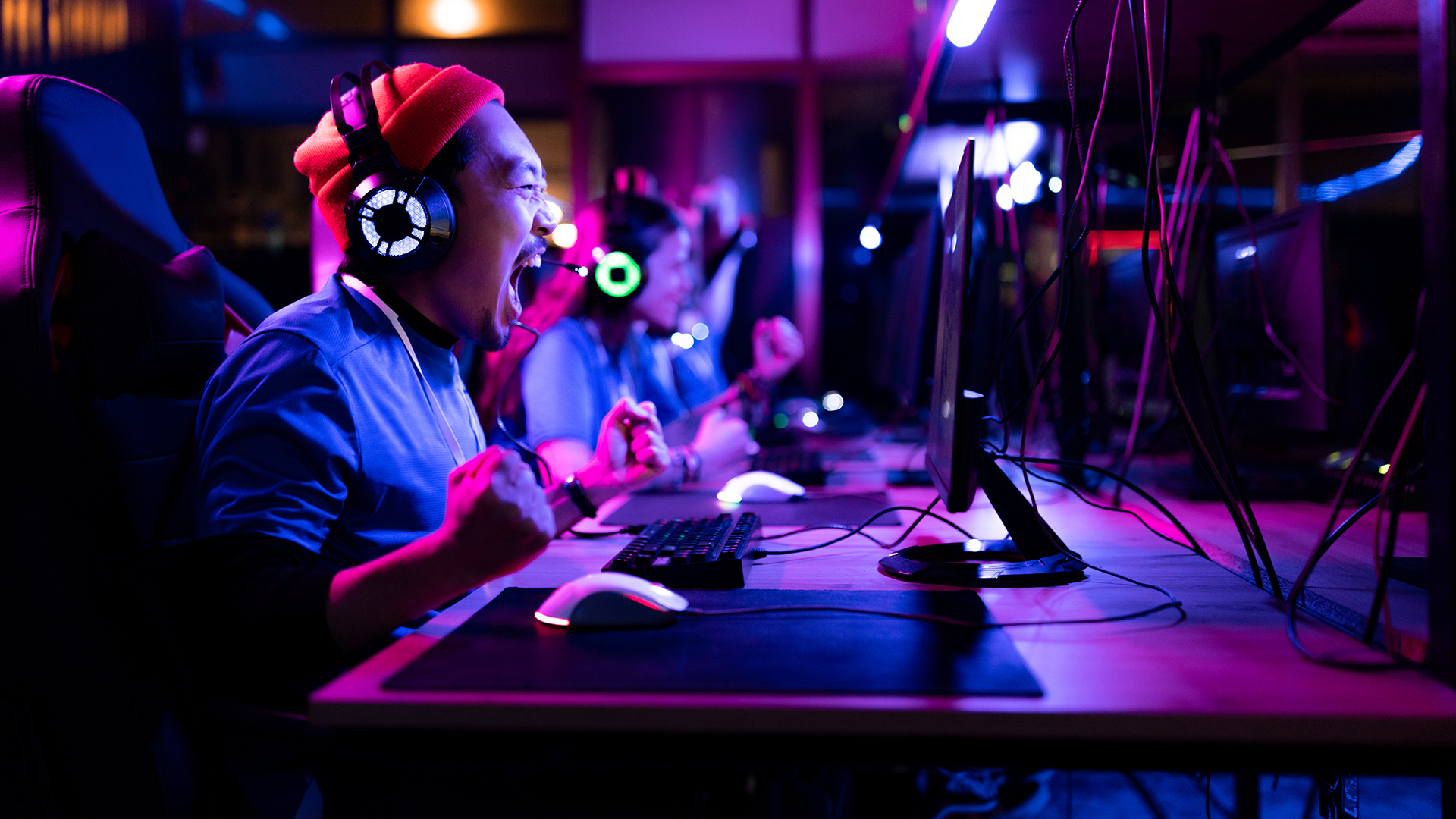Cheerful Chinese man screaming of joy after winning in eSports video games at entertainment club.