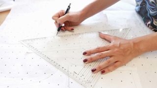 image of a person using a mechanical pencil on a piece of paper with a set square