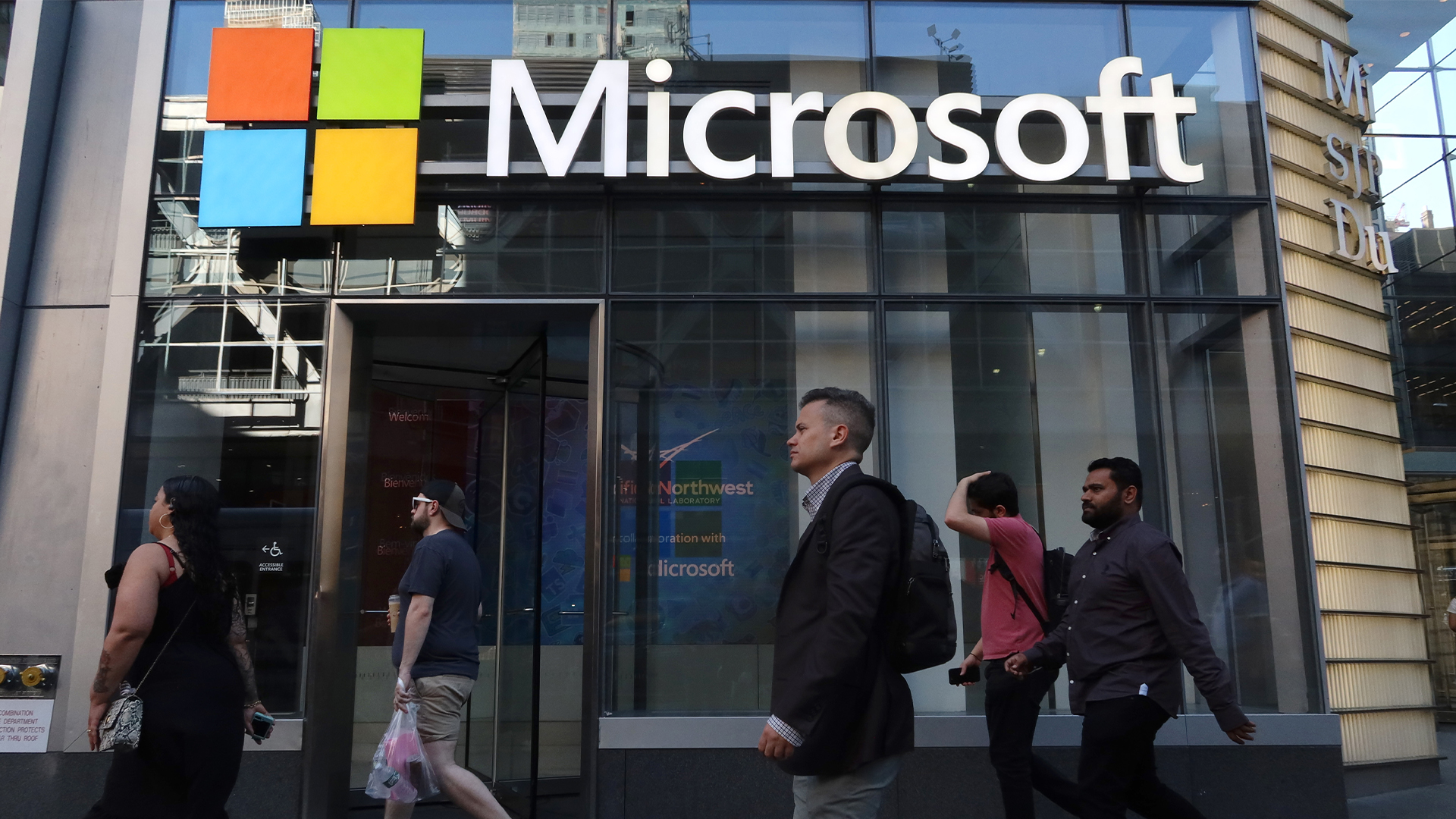 Pedestrians walk by the entrance to a Microsoft office building on 8th Avenue in New York City, USA.