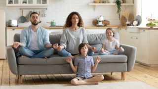 Relaxed young family with cute children sitting and meditating