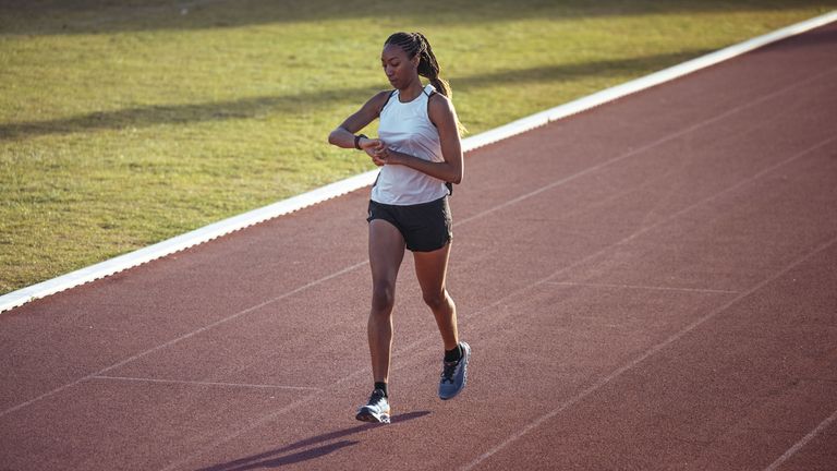 fit female runner looking at the Polar Pacer Pro on a running track