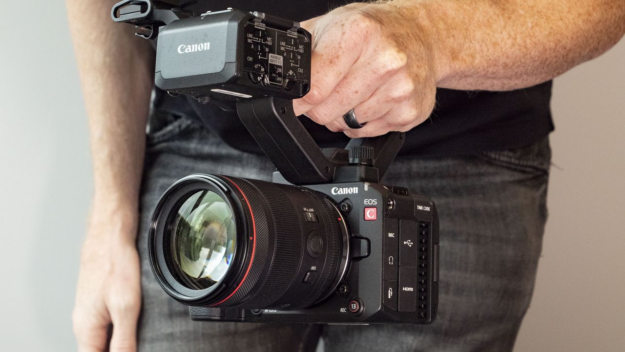 Canon EOS C50 with top handle, held by a filmmaker
