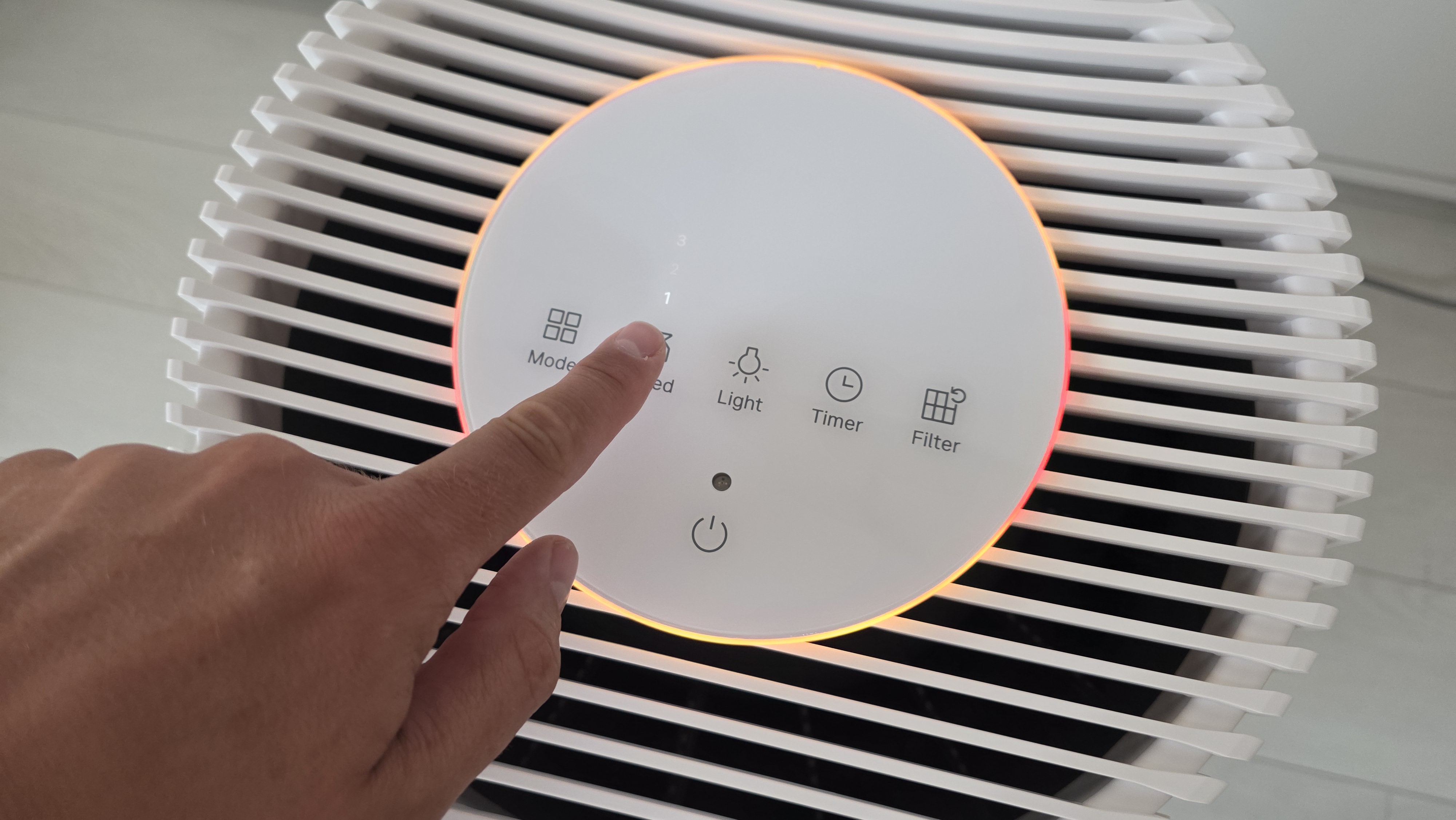 A man's hand presses the touch sensitive Speed button on top surface of the Coway Airmega 350.