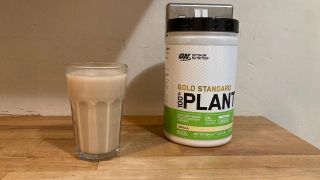 Optimum Nutrition Gold Standard 100% Plant Protein shake mixed in glass with tub
