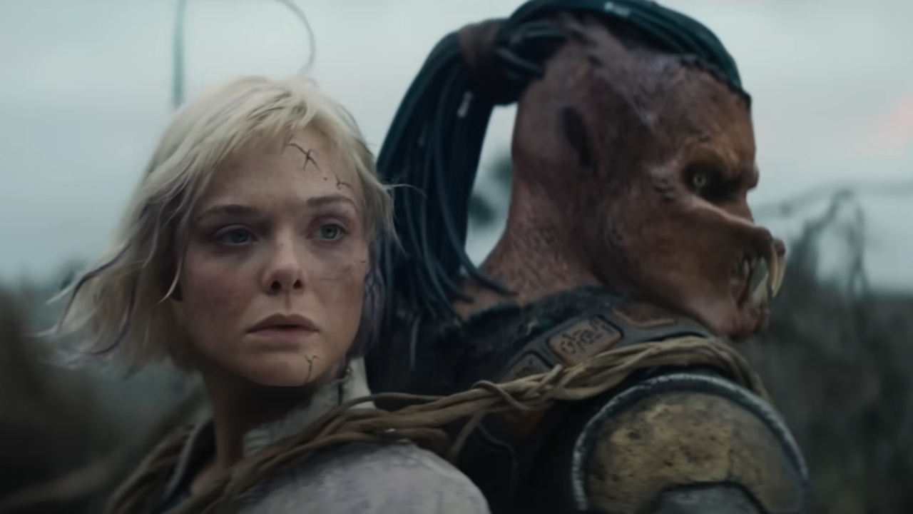 Screenshot from the movie Predator: Badlands. Close up of a Predator and a female synth, back to back.