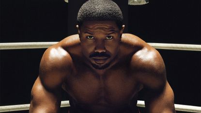Michael B. Jordan as Adonis Creed, sitting in the corner of a boxing ring