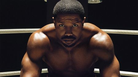 Michael B. Jordan as Adonis Creed, sitting in the corner of a boxing ring