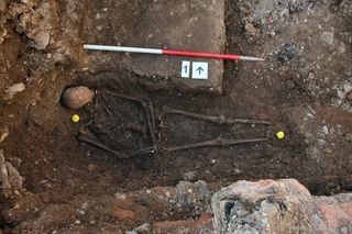 King Richard III of England in his original grave, discovered in 2012 beneath a parking lot in Leicester. The king was buried hastily after his death in the Battle of Bosworth Field in 1485.