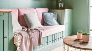 Sage green living room with pink sofa cushions