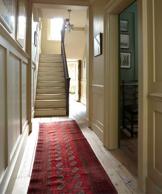 farrow & ball painted yellow hallway with a red runner rug