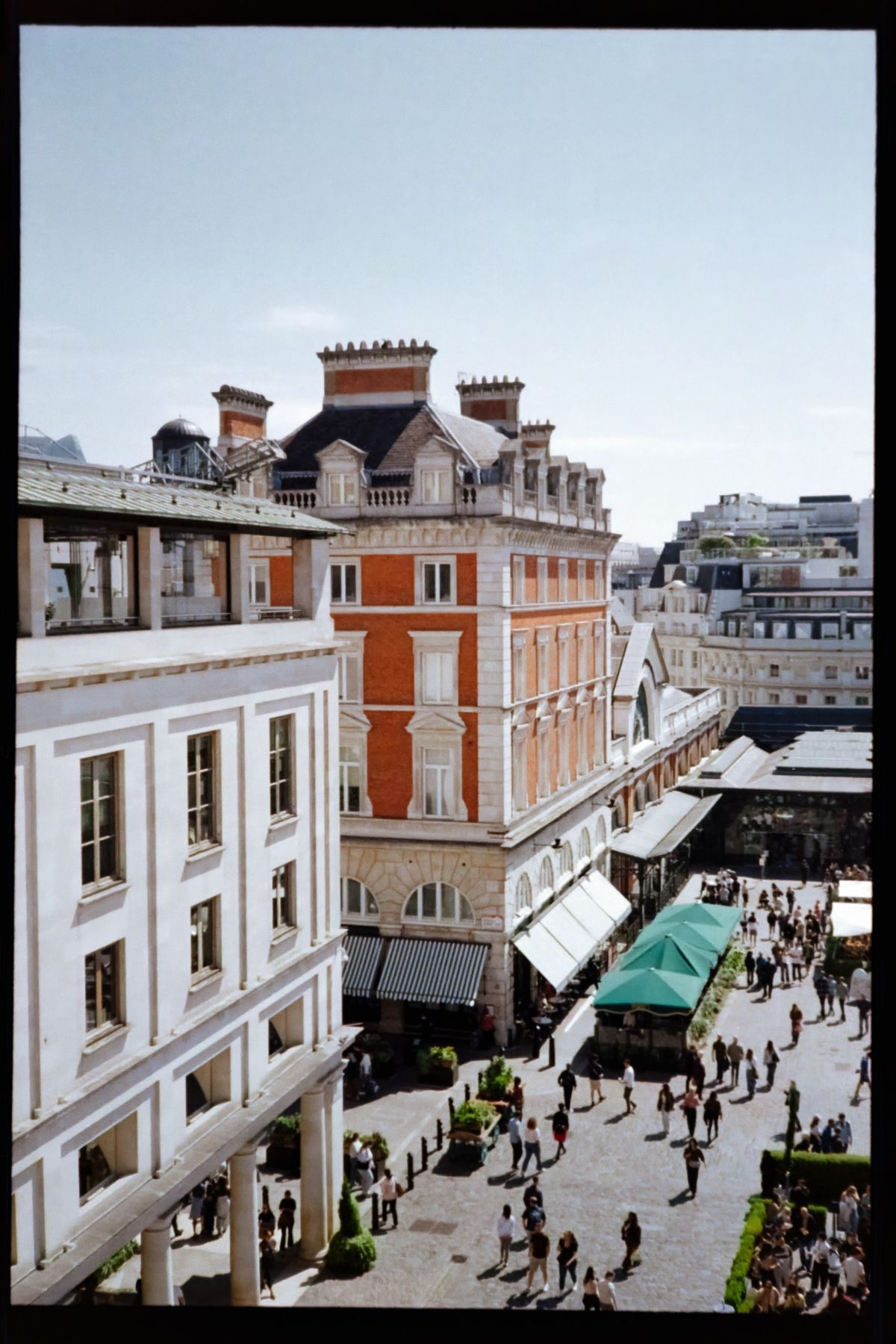 Scanned film photograph looking down into a busy urban courtyard surrounded by historic buildings, caf&eacute;s, and pedestrians.