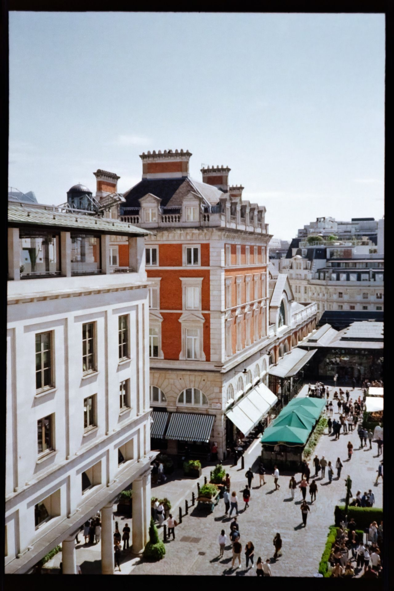 Scanned film photograph looking down into a busy urban courtyard surrounded by historic buildings, caf&eacute;s, and pedestrians.