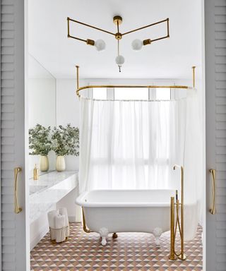 A bathroom with a free standing white bath and geometric floor tiles