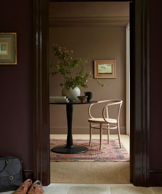 doorway with dark brown walls leading into light brown room with table