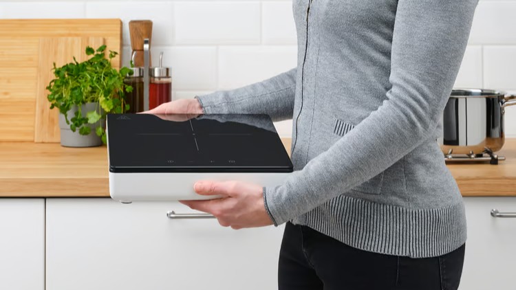 Woman holding IKEA Tillreda portable induction stove