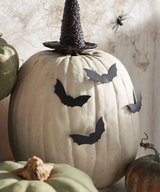 white large pumpkin with bat decals and a rattan witches hat