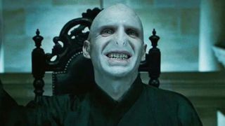 Voldemort bares his teeth, sitting in a black throne