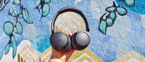 1More SonoFlow SE headphones held against a colorful backdrop